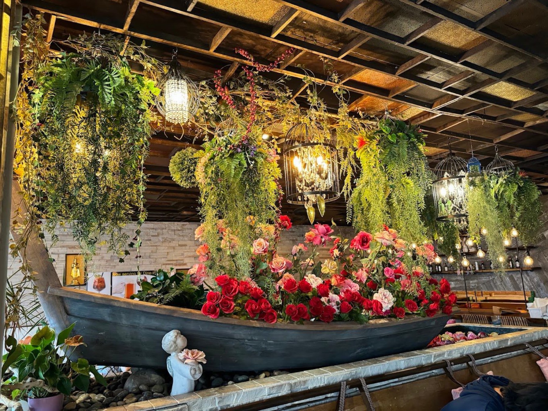 Thai Princess dining room, with a floral boat display and hanging greenery under the wood ceiling